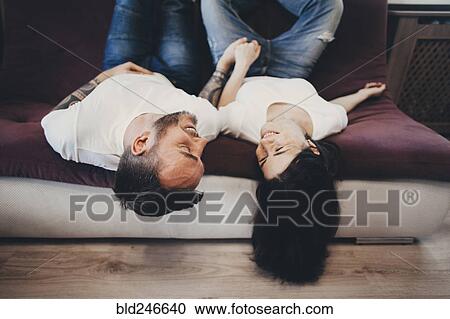 Caucasian couple laying upside-down on sofa View Large Photo Image Stock Image - Caucasian couple laying upside-down on sofa. Fotosearch