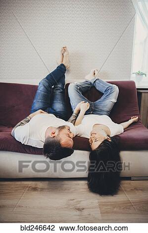 Caucasian couple laying upside-down on sofa View Large Photo Image Stock Image - Caucasian couple laying upside-down on sofa. Fotosearch
