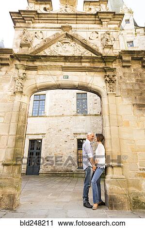 Stock Image - Caucasian couple leaning in arch. Fotosearch