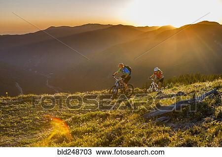 Stock Image - Caucasian couple mountain biking. Fotosearch