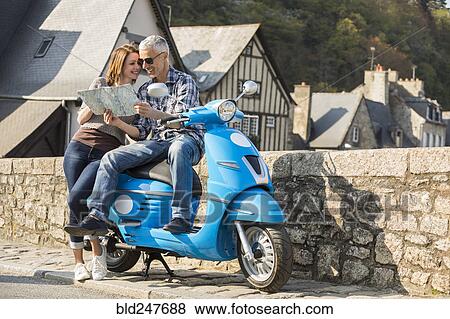 Stock Photo - Caucasian couple on blue motor scooter reading map. Fotosearch