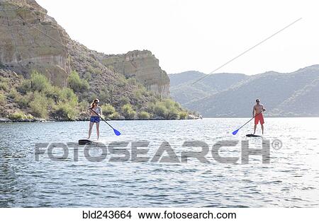 Picture - Caucasian couple on paddleboards in river. Fotosearch