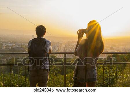 Stock Photography - Caucasian couple photographing scenic view of cityscape. Fotosearch