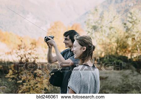 Caucasian couple photographing with camera in autumn View Large Photo Image Stock Image - Caucasian couple photographing with camera in autumn. Fotosearch