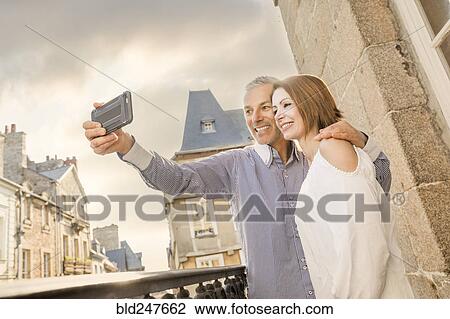 Stock Image - Caucasian couple posing for cell phone selfie. Fotosearch