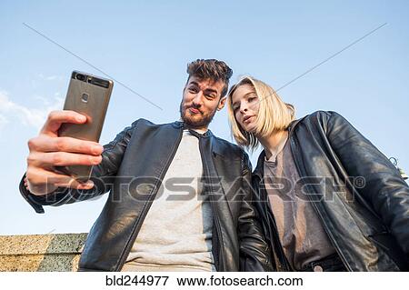 Stock Photo - Caucasian couple posing for cell phone selfie. Fotosearch