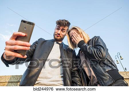 Stock Photograph - Caucasian couple posing for cell phone selfie. Fotosearch