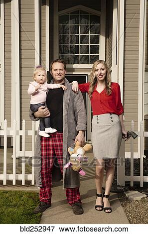 Stock Photo - Caucasian couple posing near house with baby daughter. Fotosearch