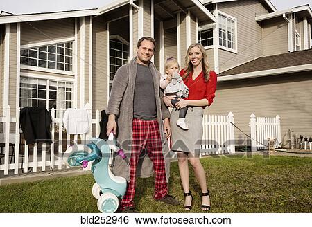 Stock Photograph - Caucasian couple posing on lawn with baby daughter. Fotosearch