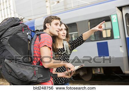 Caucasian couple reading map near train and pointing View Large Photo Image Stock Photograph - Caucasian couple reading map near train and pointing. Fotosearch