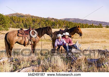 Stock Photo - Caucasian couple relaxing in field with horses. Fotosearch
