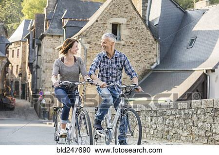 Stock Image - Caucasian couple riding bicycles in city. Fotosearch