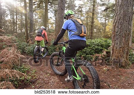 Stock Photo - Caucasian couple riding bicycles in forest. Fotosearch