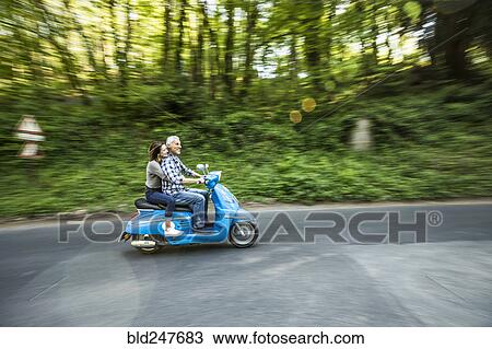 Caucasian couple riding blue motor scooter View Large Photo Image Stock Image - Caucasian couple riding blue motor scooter. Fotosearch