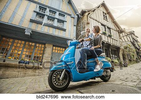 Stock Photograph - Caucasian couple riding blue motor scooter. Fotosearch