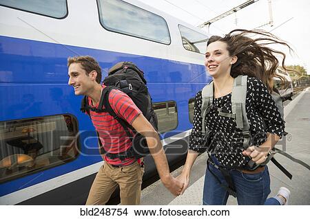 Picture - Caucasian couple running near train. Fotosearch