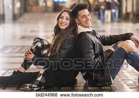 Stock Photo - Caucasian couple sitting back to back on lobby floor. Fotosearch