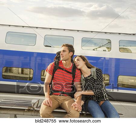 Stock Photography - Caucasian couple sitting on bench near train. Fotosearch