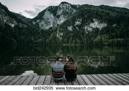 Caucasian couple sitting on dock near scenic view of mountain View Large Photo Image Stock Photography - Caucasian couple sitting on dock near scenic view of mountain. Fotosearch
