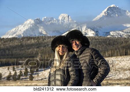 Stock Image - Caucasian couple smiling near mountains in winter. Fotosearch