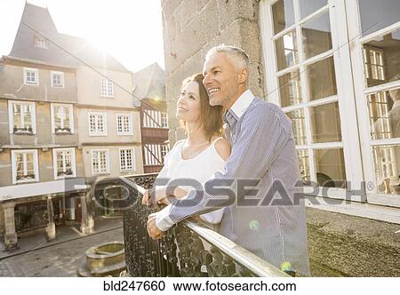 Stock Image - Caucasian couple smiling on balcony in city. Fotosearch