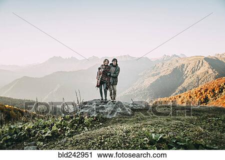 Caucasian couple standing on mountain rock overlooking valley View Large Photo Image Stock Image - Caucasian couple standing on mountain rock overlooking valley. Fotosearch