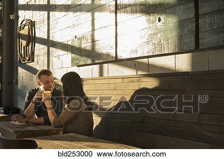 Stock Image - Caucasian couple talking in brew pub. Fotosearch