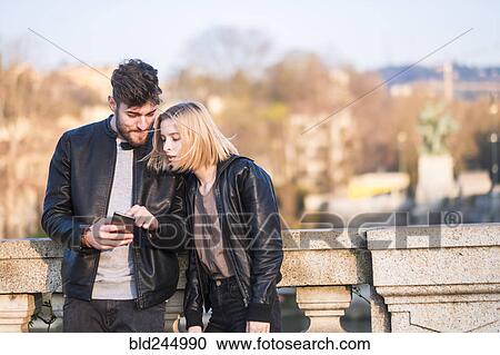 Caucasian couple texting on cell phone outdoors View Large Photo Image Stock Image - Caucasian couple texting on cell phone outdoors. Fotosearch