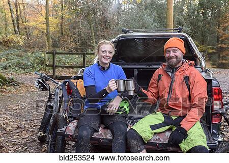 Picture - Caucasian couple toasting with coffee cups in pickup truck. Fotosearch