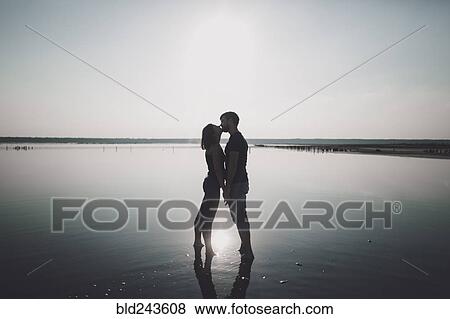 Caucasian couple wading in lake and kissing View Large Photo Image Stock Photo - Caucasian couple wading in lake and kissing. Fotosearch