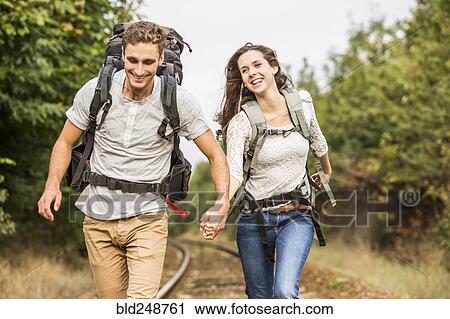 Stock Image - Caucasian couple walking on train tracks. Fotosearch