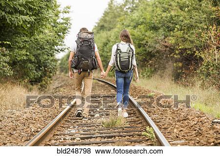 Stock Photo - Caucasian couple walking on train tracks. Fotosearch