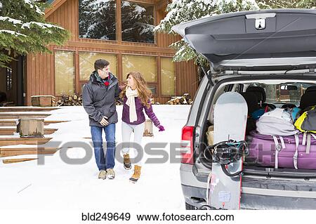 Stock Photo - Caucasian couple walking to car at winter resort. Fotosearch