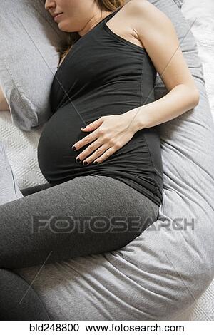 Caucasian expectant mother laying on bed with support pillow View Large Photo Image Stock Image - Caucasian expectant mother laying on bed with support pillow. Fotosearch