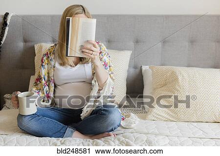 Caucasian expectant mother sitting on bed reading book and drinking coffee View Large Photo Image Stock Image - Caucasian expectant mother sitting on bed reading book and drinking coffee. Fotosearch