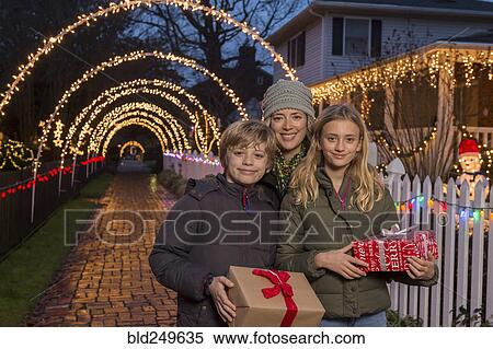 Stock Photography - Caucasian family holding Christmas gifts on sidewalk. Fotosearch