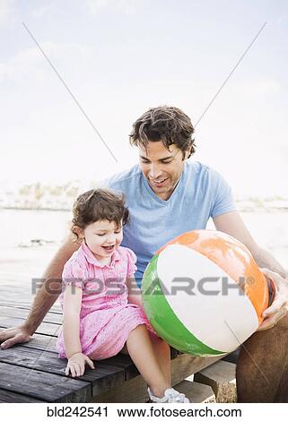 Caucasian father and baby daughter sitting on dock with beach ball View Large Photo Image Stock Image - Caucasian father and baby daughter sitting on dock with beach ball. Fotosearch