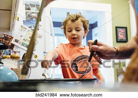 Picture - Caucasian father and son cooking on stove. Fotosearch