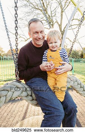 Stock Photography - Caucasian father and son playing on swing. Fotosearch