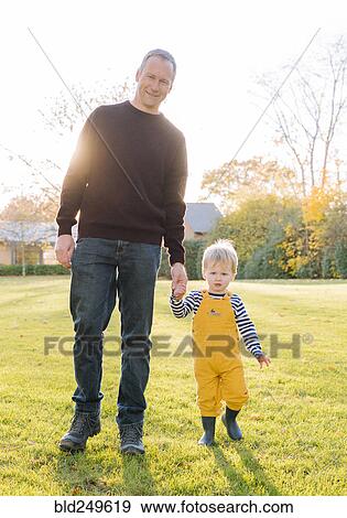 Stock Photo - Caucasian father and son walking in field. Fotosearch