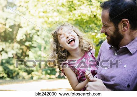 Stock Image - Caucasian father carrying laughing, daughter. Fotosearch