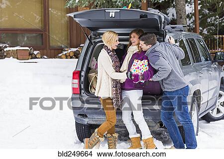 Caucasian friends laughing with gifts at car in winter View Large Photo Image Picture - Caucasian friends laughing with gifts at car in winter. Fotosearch