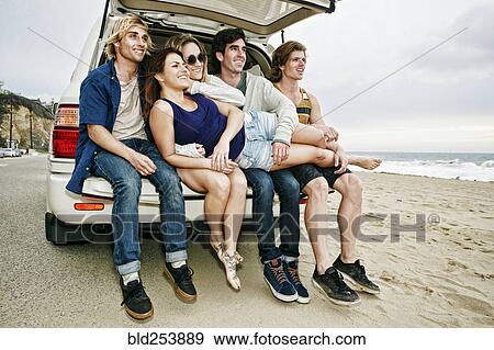 Caucasian friends sitting in car hatch at beach View Large Photo Image Stock Photo - Caucasian friends sitting in car hatch at beach. Fotosearch