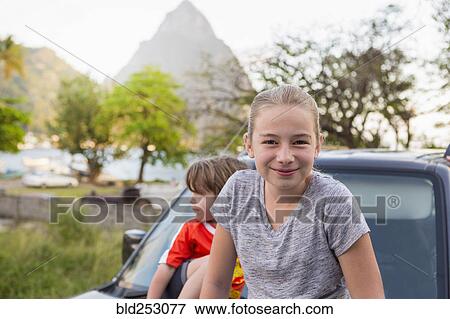 Stock Photo - Caucasian girl and boy sitting on hood of car. Fotosearch