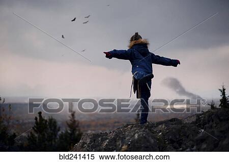 Stock Photography - Caucasian girl balancing on rocks imitating flying birds. Fotosearch