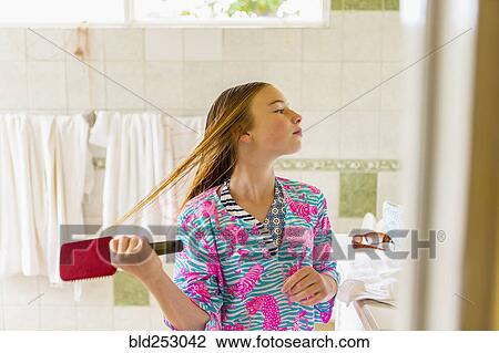 Stock Image - Caucasian girl brushing wet hair in bathroom. Fotosearch