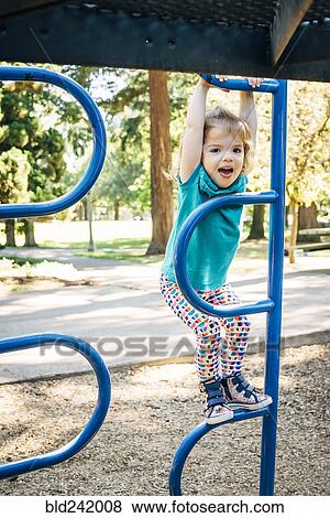 Stock Photo - Caucasian girl climbing on playground structure. Fotosearch