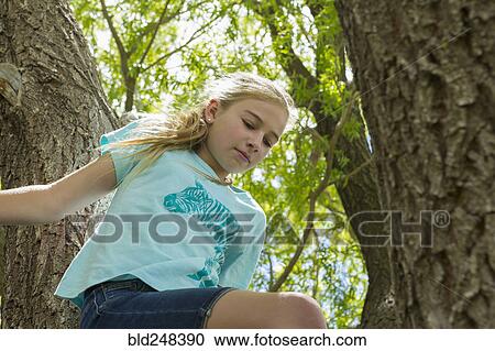 Stock Image - Caucasian girl climbing tree. Fotosearch