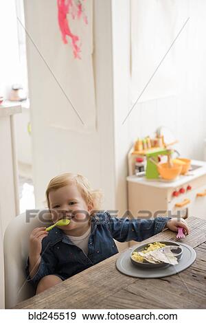 Stock Photo - Caucasian girl eating with fork and spoon. Fotosearch