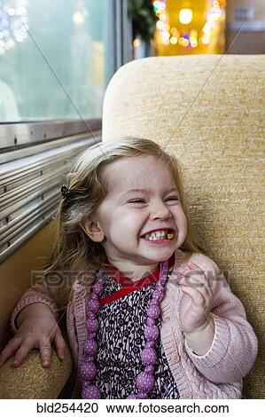 Stock Image - Caucasian girl grinning near window on train. Fotosearch